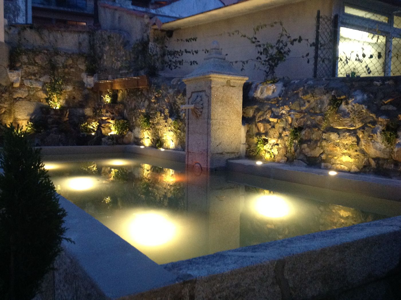 Fonte em pedra com iluminação subaquática e de muro